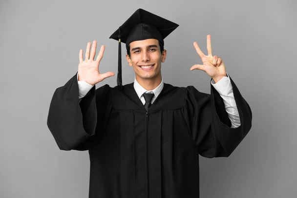 Młody argentyński absolwent uniwersytetu odizolowany na szarym tle licząc osiem palców - Zdjęcie, obraz