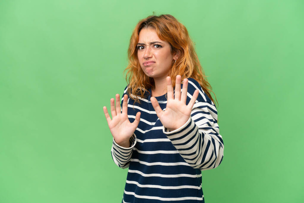 Молода біла жінка ізольована на зеленому екрані хром ключ фон нервовий розтягування рук на передній план
 - Фото, зображення