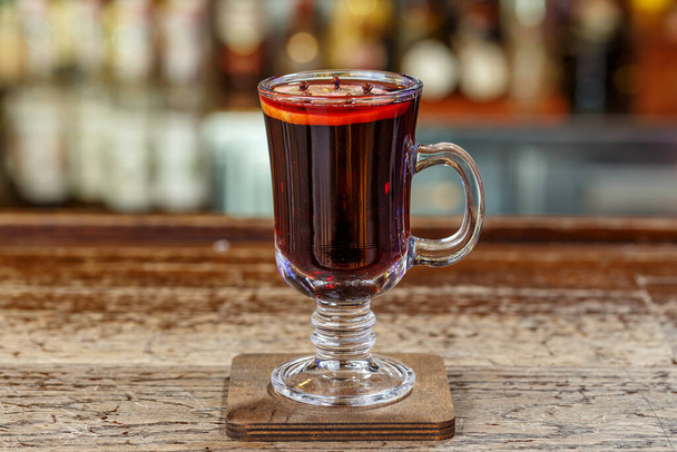 Mulled wine in a glass, a hot alcoholic drink stands on a wooden bar counter in a restaurant - Fotó, kép