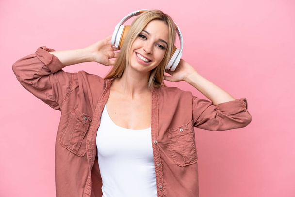 Pretty blonde woman isolated on pink background listening music - Foto, immagini