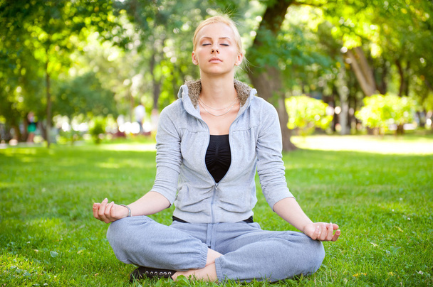 Portrait of young woman meditating in pose of lotus on green gra - Photo, Image