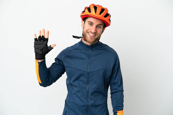 Young cyclist man isolated on white background saluting with hand with happy expression - Photo, Image