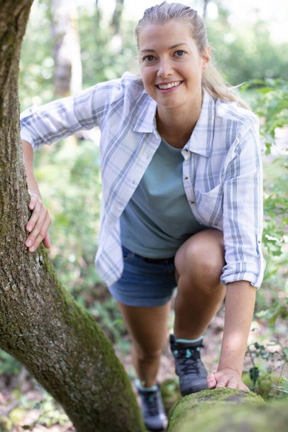 woman hiking is climbing over tree trunk - Foto, Imagem