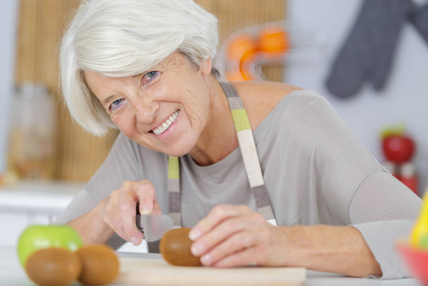 donna anziana che taglia pomodori in cucina - Foto, immagini
