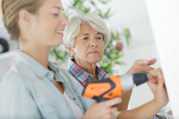 young woman holding screwdriver next to her mum - Foto, Imagen
