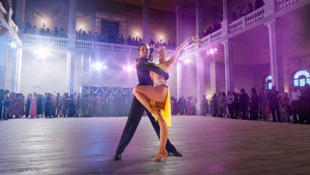 Пара танцоров танцуют латинский танец на большой профессиональной сцене. - Фото, изображение