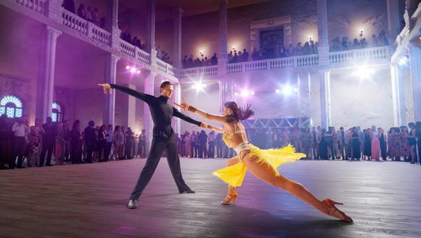Пара танцоров танцуют латинский танец на большой профессиональной сцене. - Фото, изображение