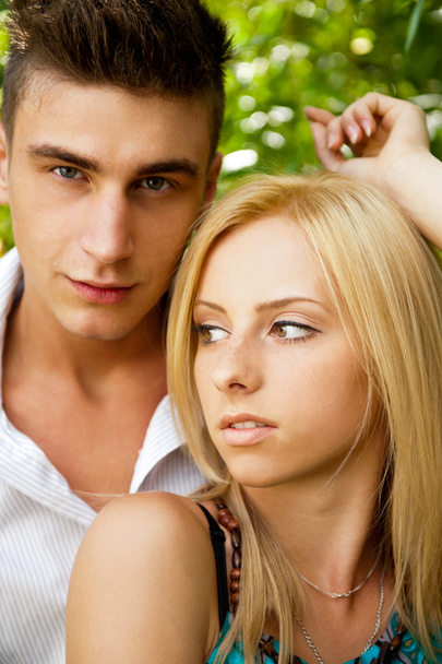 Portrait of beautiful young couple standing against green tree i - Photo, image