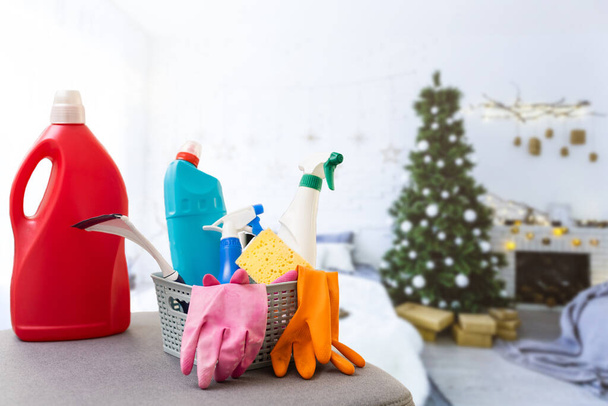 Aufräumen vor Weihnachten. Bunte Putzmittel. Schwämme, Lumpen und Spray mit festlicher Dekoration vor modernem Wohnhintergrund - Foto, Bild