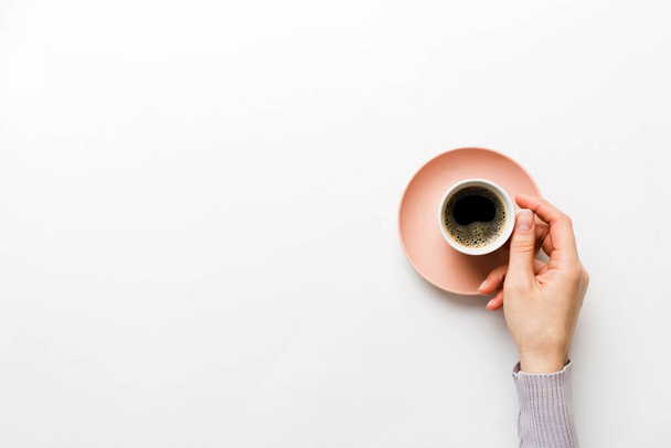 Minimalistyczny styl kobieta ręka trzyma filiżankę kawy na kolorowym tle. Płaska, górny widok filiżanka cappuccino. Puste miejsce na tekst, miejsce na ksero. Uzależnienie od kawy. Widok z góry, płaski. - Zdjęcie, obraz