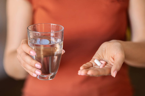 Nerozpoznatelná žena drží sklenici vody a hromádky pilulek v ruce, Closeup Shot of Female přičemž vitamínové doplňky pro krásu a imunitu nebo získání lékařské ošetření, oříznutý obrázek - Fotografie, Obrázek
