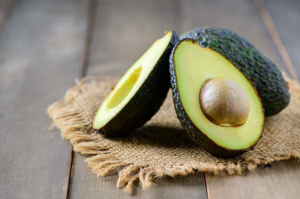 Verse avocado op hout achtergrond, rijk aan vitaminen en mineralen, zoals vitamine B helpt voorkomen beriberi, vitamine C helpt versterken het immuunsysteem - Foto, afbeelding