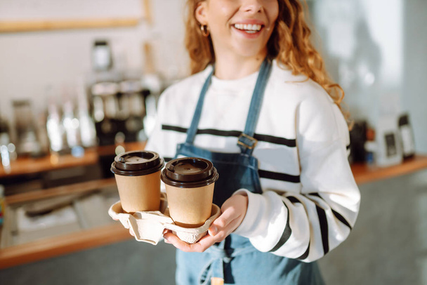 offee to go. Young barista girl smiling happy holding take away coffee at the cafe shop. - Foto, Imagem