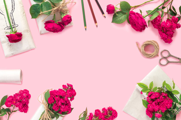 Zestaw papieru do pakowania i kwiatów do ręcznie robionego na różowym tle. Domowe rzemieślnicze pudełko prezenty z bukietem czerwonych róż - Zdjęcie, obraz