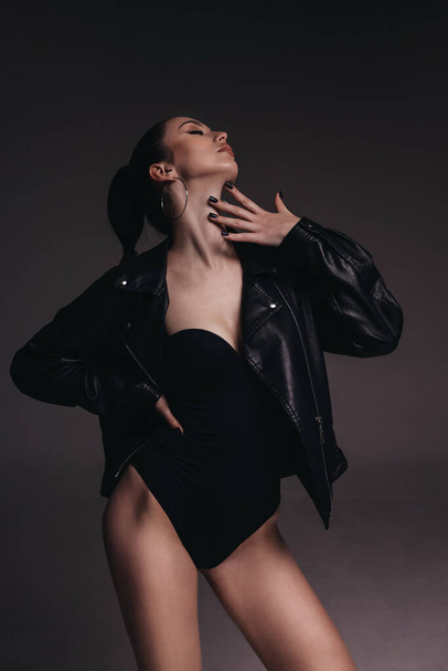 fashion photo of beautiful woman with dark hair in elegant clothes and black leather jacket - 写真・画像
