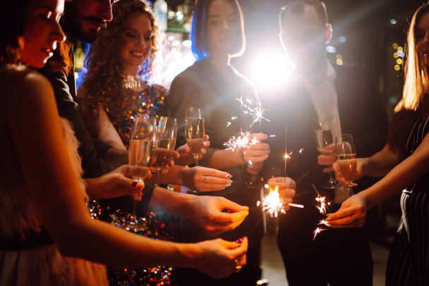 Sparkling sparklers in the hands of friends.Group of people holding sparklers at party. Winter holidays, vacation, relax and lifestyle concept. - Photo, Image