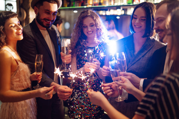 Sparkling sparklers in the hands of friends.Group of people holding sparklers at party. Winter holidays, vacation, relax and lifestyle concept. - 写真・画像
