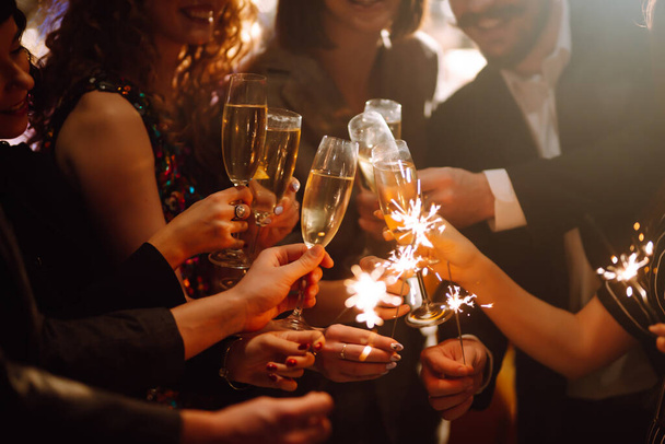 Sparkling sparklers in the hands of friends.Group of people holding sparklers at party. Winter holidays, vacation, relax and lifestyle concept. - 写真・画像