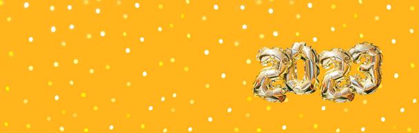 Palloncino d'oro di elio numero dell'anno 2023. Ghirlanda festiva lucente con bokeh su sfondo arancione. Felice anno nuovo banner - Foto, immagini