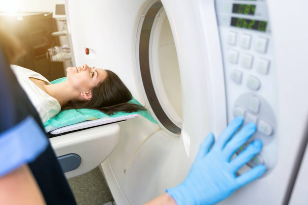 CT σαρωτής τεχνολόγος με θέα ασθενή σε αξονική τομογραφία σαρωτή κατά τη διάρκεια της προετοιμασίας για τη διαδικασία. Γυναίκα ασθενής πηγαίνει σε αξονική τομογραφία - Φωτογραφία, εικόνα
