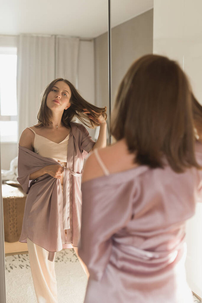 Buenos días. Atractiva joven mujer mirando en el espejo en su apartamento. - Foto, Imagen