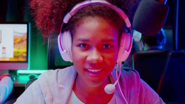 ヘッドセットを身に着けている若いアフリカ系アメリカ人の女性とチームは、家庭、ゲームやスポーツやキャスティングゲーム、放送やエンターテイメントのコンセプトでマイクでオンラインでビデオゲームやライブストリーミングをプレイ. - 映像、動画