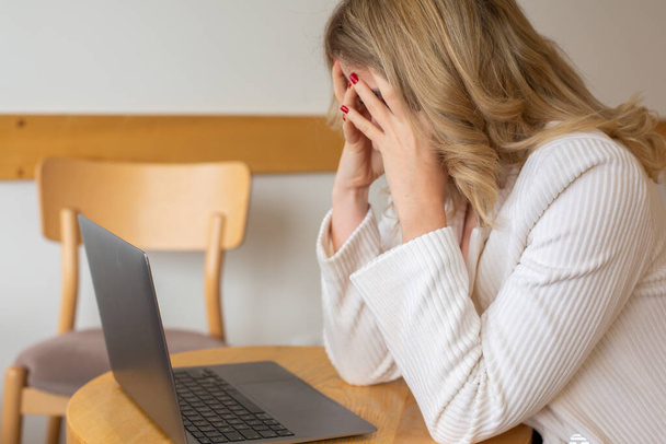 Девушка-фрилансер чувствует усталость и стресс, пользуясь ноутбуком и работая дома. Деловая женщина в офисе в депрессии.  - Фото, изображение