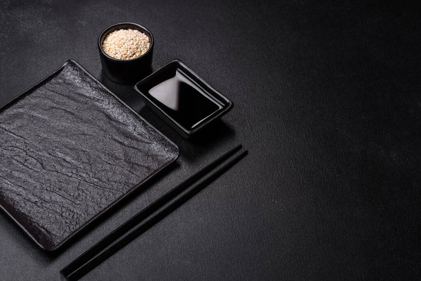 Κενό πιάτο με ξύλινα ραβδιά για ασιατικό φαγητό σε σκούρο φόντο από τσιμέντο. Προετοιμασία της ασιατικής κουζίνας - Φωτογραφία, εικόνα