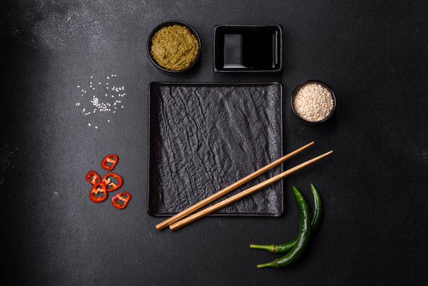 Empty plate with wooden sticks for Asian food on a dark concrete background. Preparation of Asian cuisine - Foto, Imagem