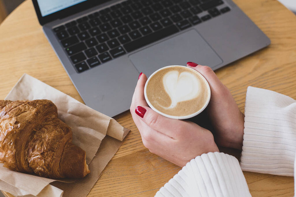 Zdjęcia kobiet trzymających papierową filiżankę kawy. Kawa na wynos. Widok z góry laptopa. Praca na własny rachunek. - Zdjęcie, obraz