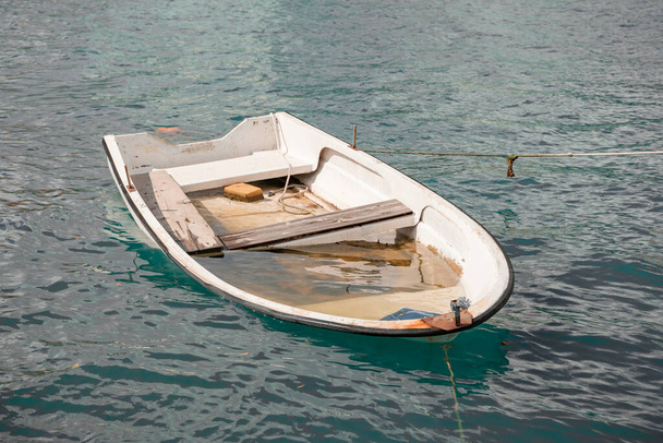 un viejo barco de pesca blanco con fugas sumergido en agua azul. Transporte de pesca acuática. - Foto, imagen
