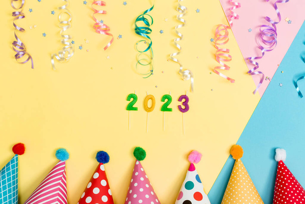 2023 party theme with with hats and streamers on a vibrant background - Fotó, kép