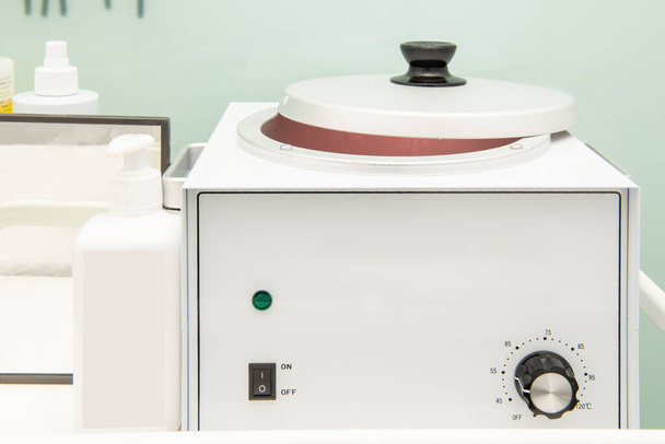 Um aquecedor de cera com um grande recipiente com uma tampa e uma roda de temperatura - Foto, Imagem