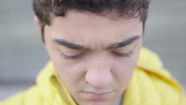 Close-up portret van trieste Spaanse tiener jongen naar beneden kijken, dan kijken naar de camera en glimlachen - Video