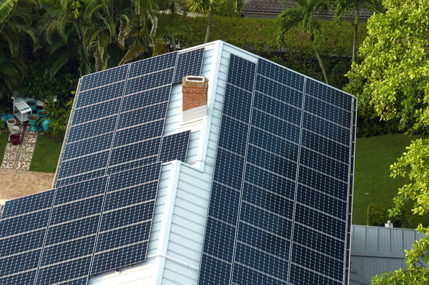 Vista aérea del nuevo techo costoso del edificio americano con filas de paneles fotovoltaicos solares azules para producir energía eléctrica ecológica limpia. Electricidad renovable con concepto de cero emisiones. - Foto, imagen
