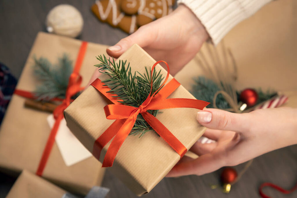 Κουτί δώρου με χριστουγεννιάτικη διακόσμηση σε γυναικεία χέρια. Κοντινό πλάνο. Έννοια των χειμερινών διακοπών - Φωτογραφία, εικόνα