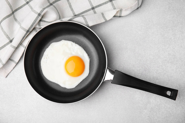 Tasty fried egg in pan on light grey table, flat lay - Photo, image