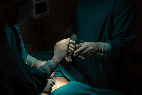 Imagen del equipo quirúrgico realiza operación quirúrgica, enfermera reparte tijeras estériles al cirujano como apoyo y cooperativo en concepto de sala de operaciones. - Foto, Imagen