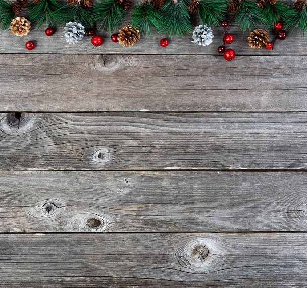 Vrolijk kerstfeest of gelukkig Nieuwjaar achtergrond met dennenboom takken en gouden zilveren dennenappels op rustieke houten planken  - Foto, afbeelding