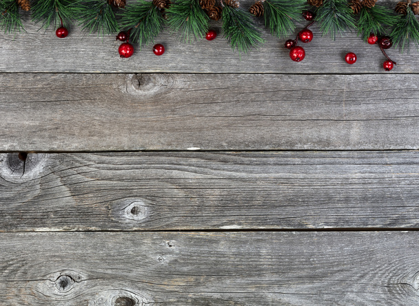 メリークリスマスまたは幸せな新年の背景にモミの先端の木の枝と素朴な木の板の上の赤い果実  - 写真・画像