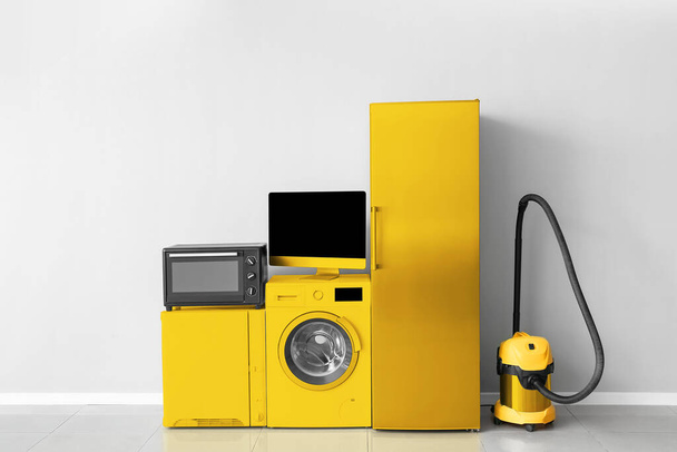 Verschiedene gelbe Haushaltsgeräte in der Nähe von Lichtwänden - Foto, Bild