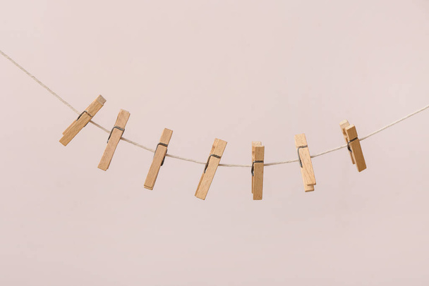 Wooden clothespins hanging on clothesline against color background - Foto, Imagen