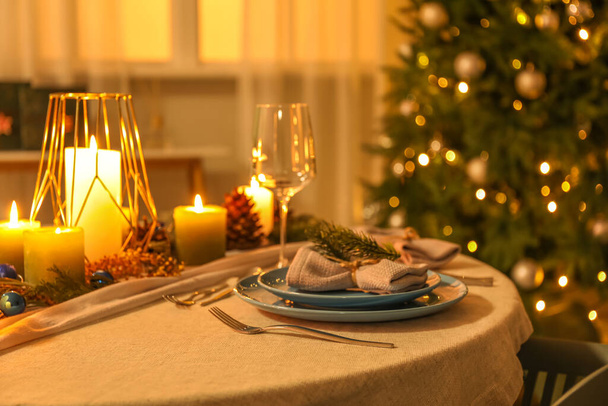 Christmas table setting with burning candles and fir branches in dining room - Фото, изображение