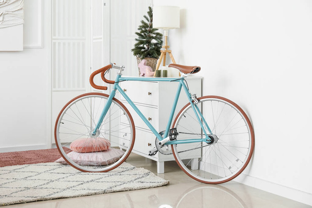 Oturma odasında Noel ağacı ve lamba olan çekmecelerin yanındaki bisiklet. - Fotoğraf, Görsel