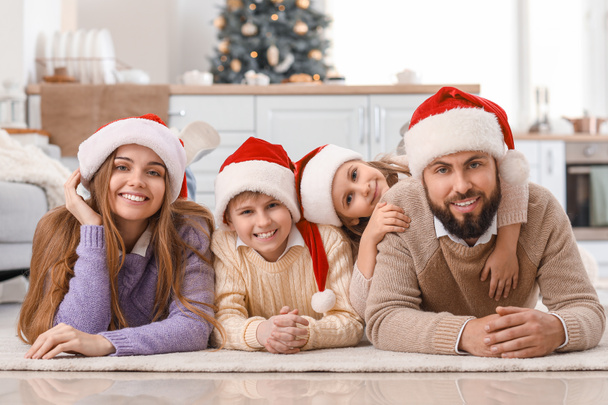 Szczęśliwa rodzina w Santa kapelusze leżące w domu w Wigilię - Zdjęcie, obraz
