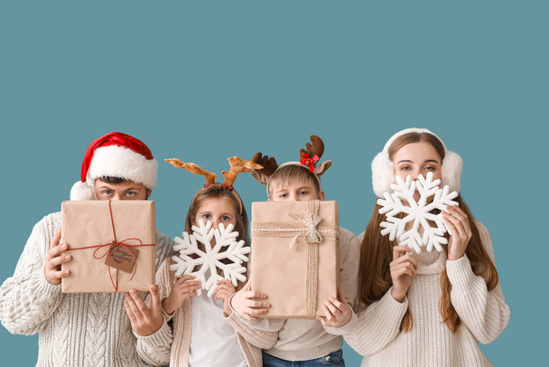 Ευτυχισμένη οικογένεια με χριστουγεννιάτικα δώρα και νιφάδες χιονιού σε μπλε φόντο - Φωτογραφία, εικόνα