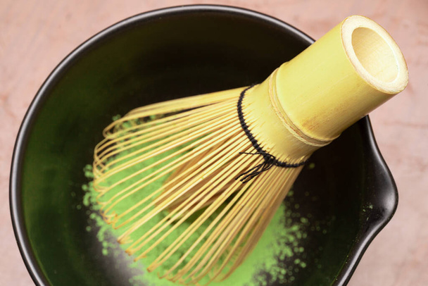 Proceso de cocción de té verde Matcha en un tazón negro con batidor de bambú. Polvo de matcha de té verde orgánico. Enfoque selectivo. - Foto, Imagen