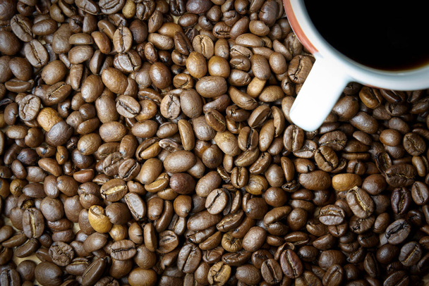 жареные кофейные зерна и чашка кофе на столе                                - Фото, изображение