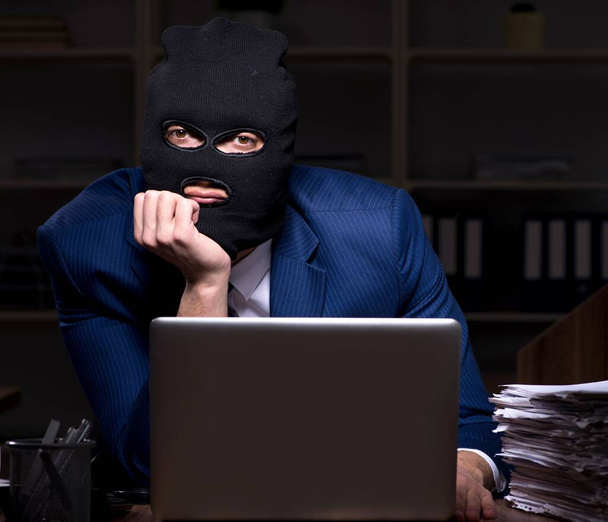 De mannelijke werknemer steelt informatie in de kantoornacht - Foto, afbeelding