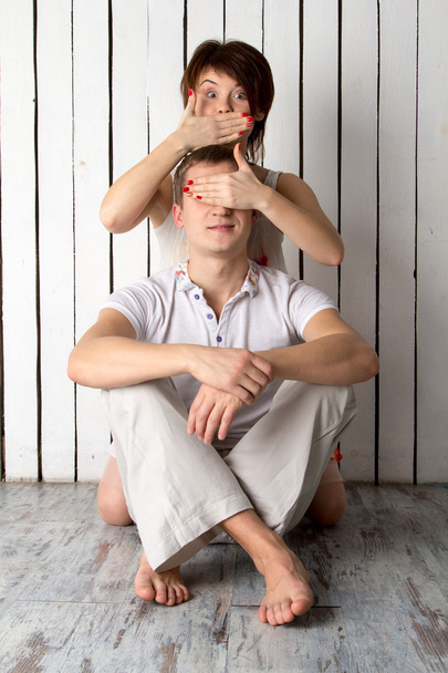 Νεαρό ζευγάρι παίζει κοντά στο λευκό ξύλινο τοίχωμα - Φωτογραφία, εικόνα
